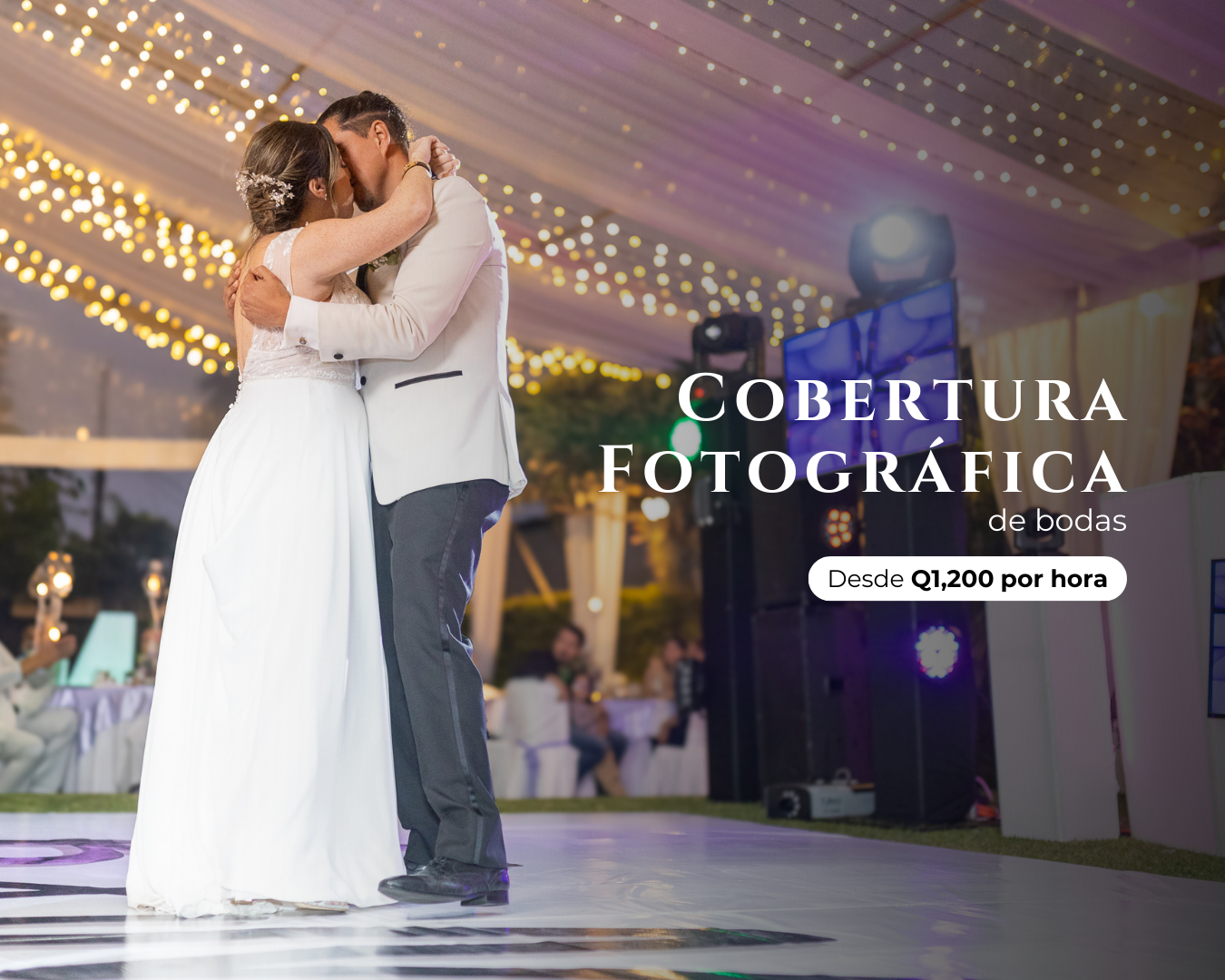 A couple shares their first dance on an illuminated dance floor under a tent with twinkling lights at their wedding reception.