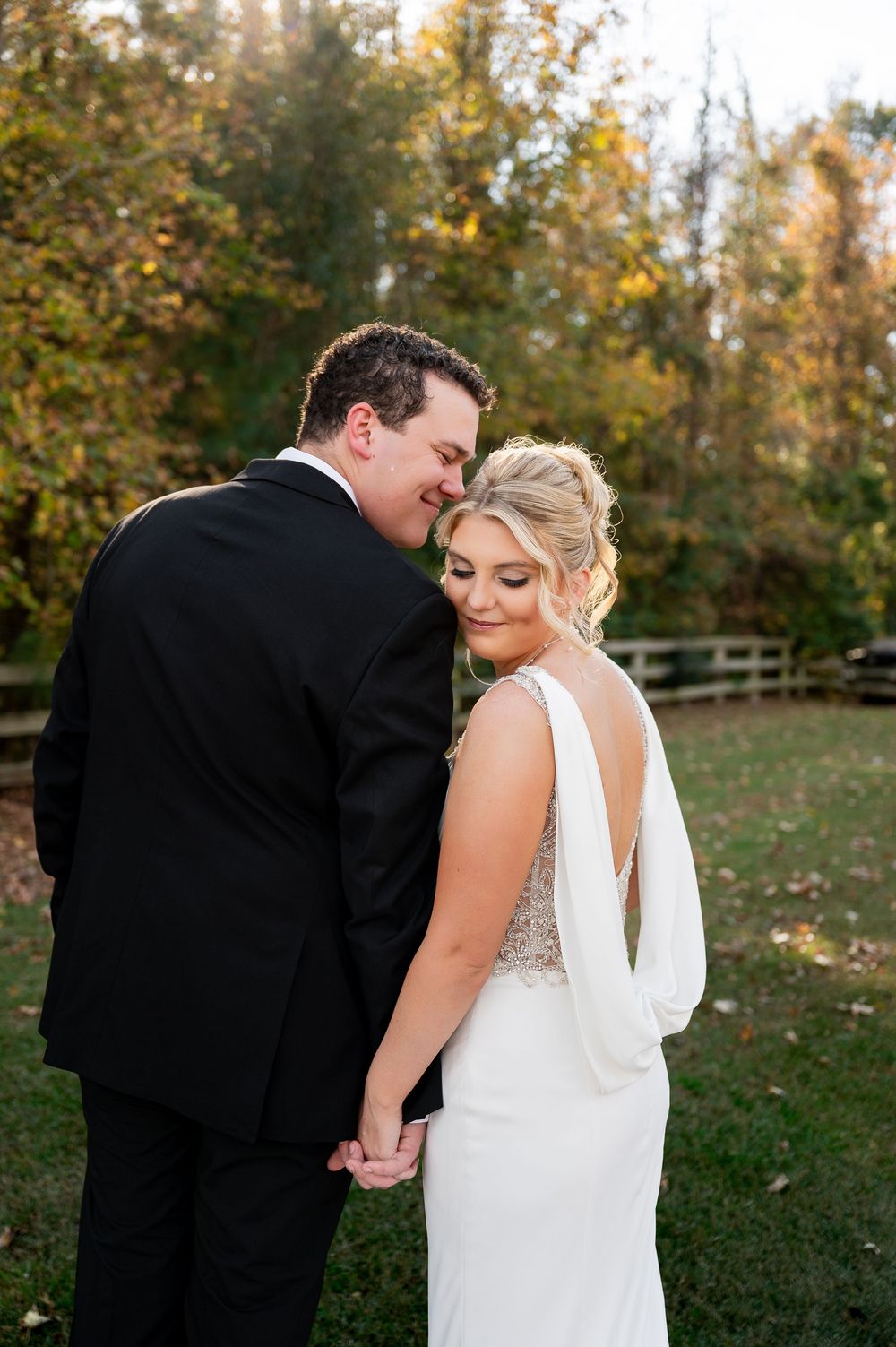 Intimate wedding portrait with couple embracing against autumn backdrop.