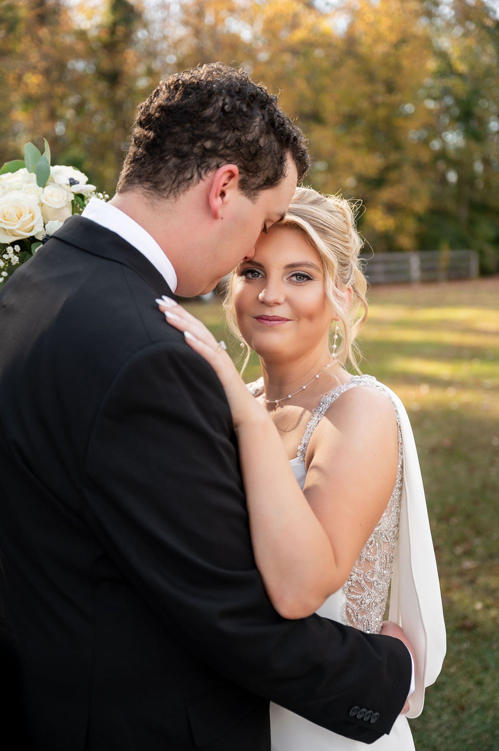 Tender embrace between newlyweds during fall outdoor photo session.