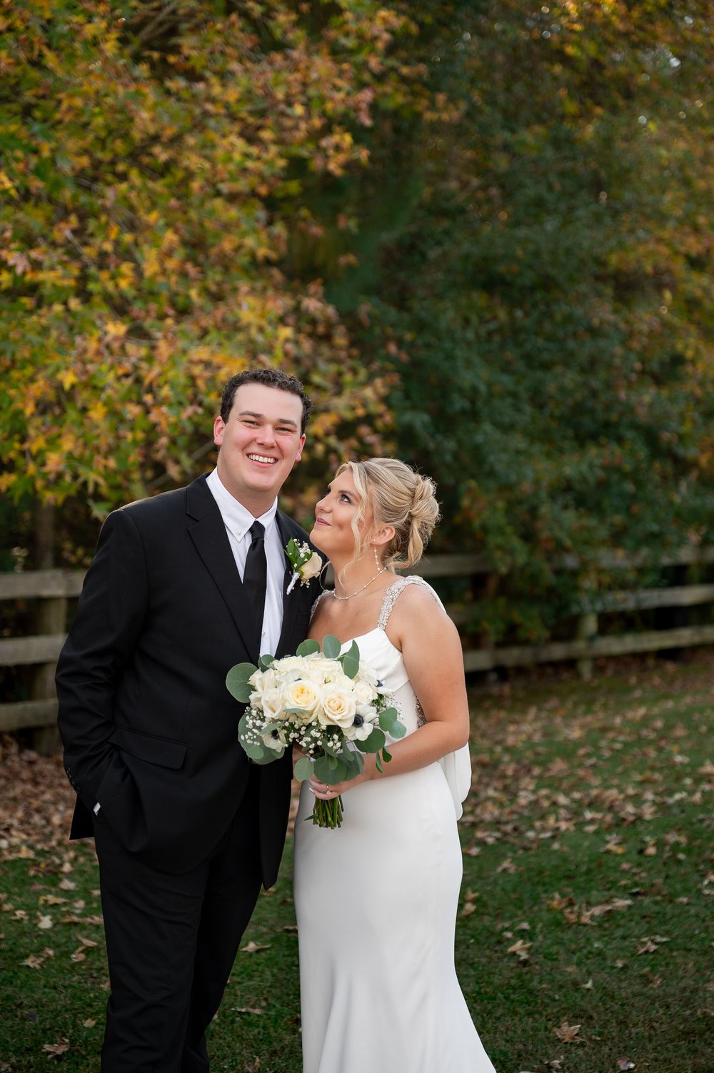 Autumn wedding portrait with white bouquet against fall foliage background.