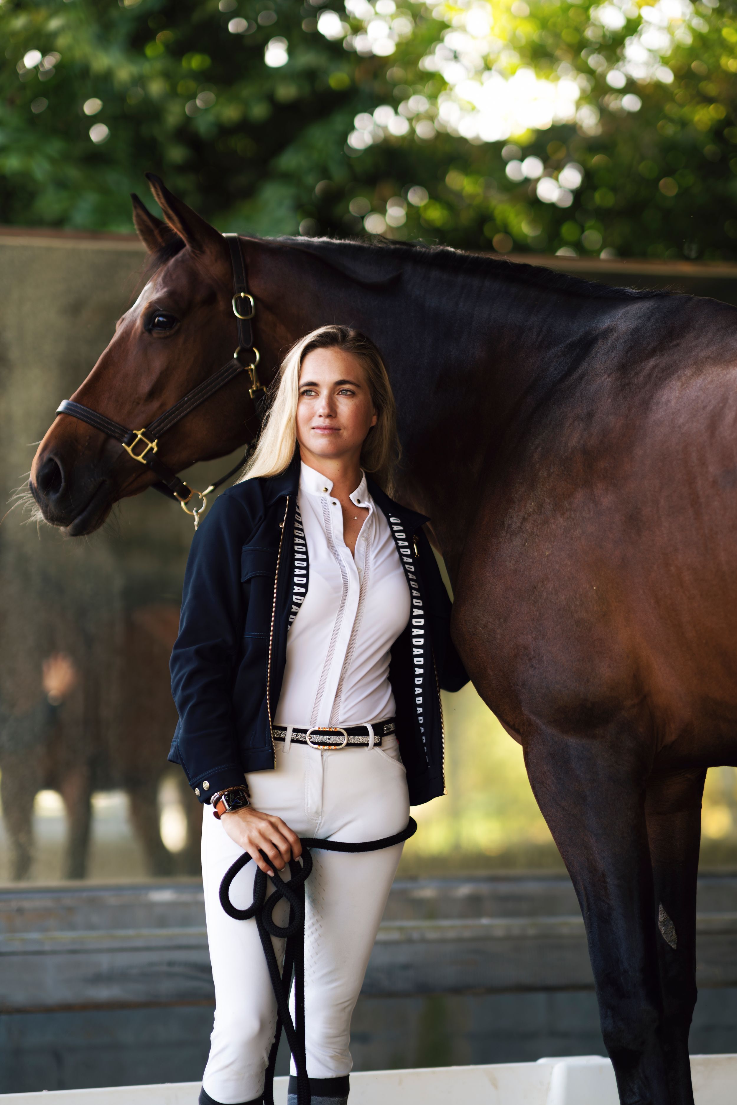 Elegant equestrian photoshoot featuring a dark bay horse and rider in contrasting navy and white attire in outdoor setting.