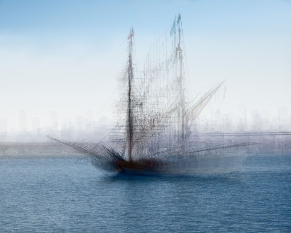 Artistic blurred impression of sailing ships on misty blue waters.