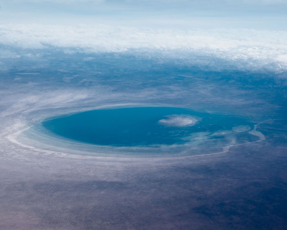 Aerial view of a large circular crater or lake formation in an arid landscape.