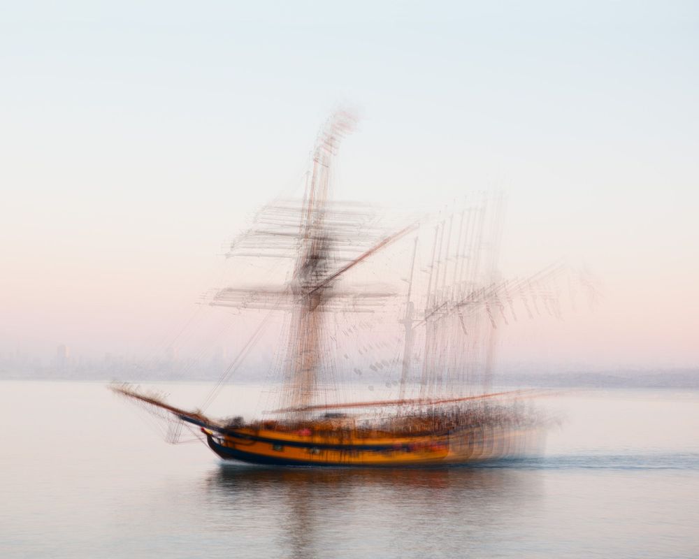 Motion-blurred sailing ship creating an artistic effect against a misty ocean backdrop.