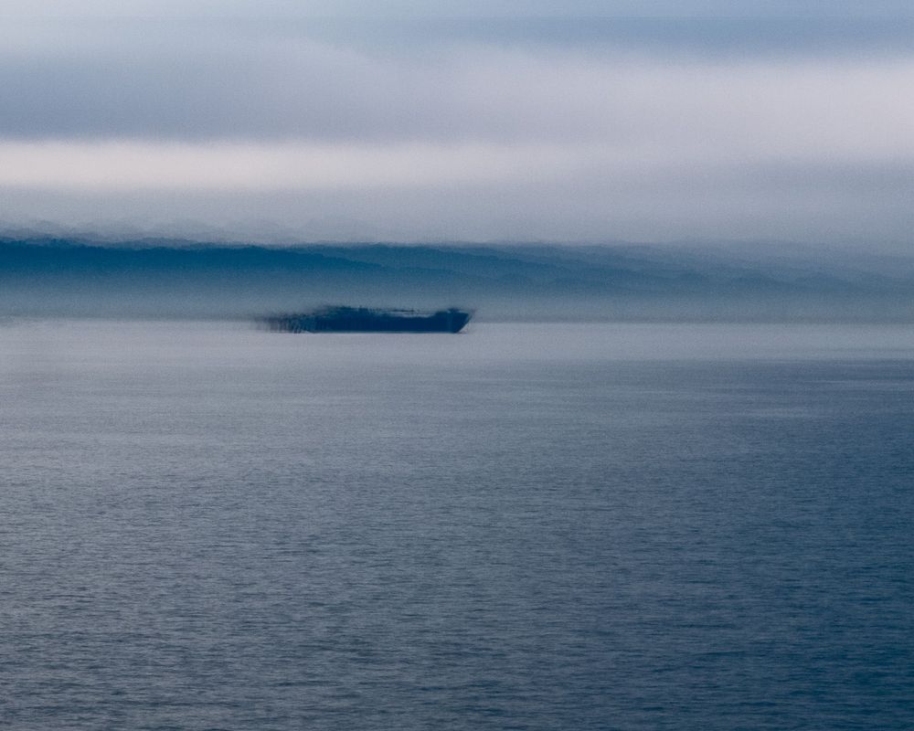 Panoramic view of calm ocean waters with distant islands on the horizon.