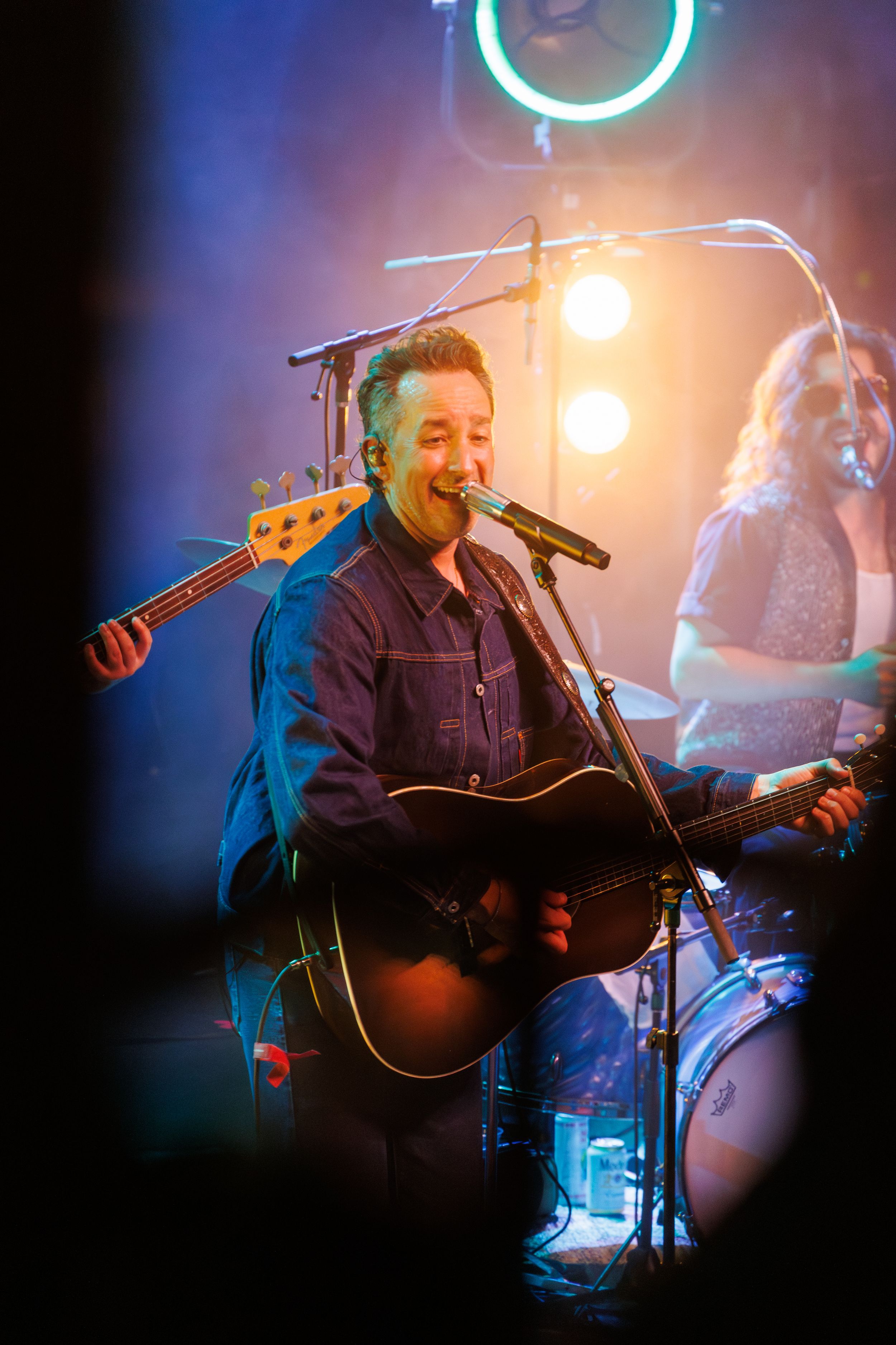 Musician performs on acoustic guitar under blue stage lighting during live concert performance.
