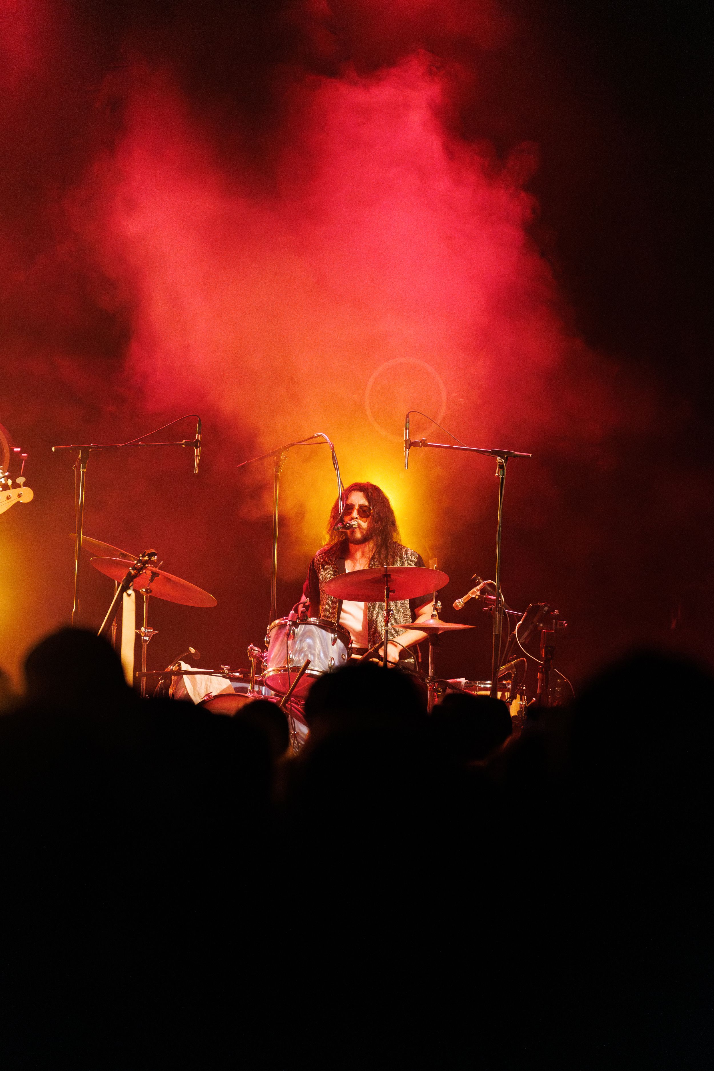 Silhouetted band performing on stage with dramatic red and orange lighting effects creating a moody atmosphere.