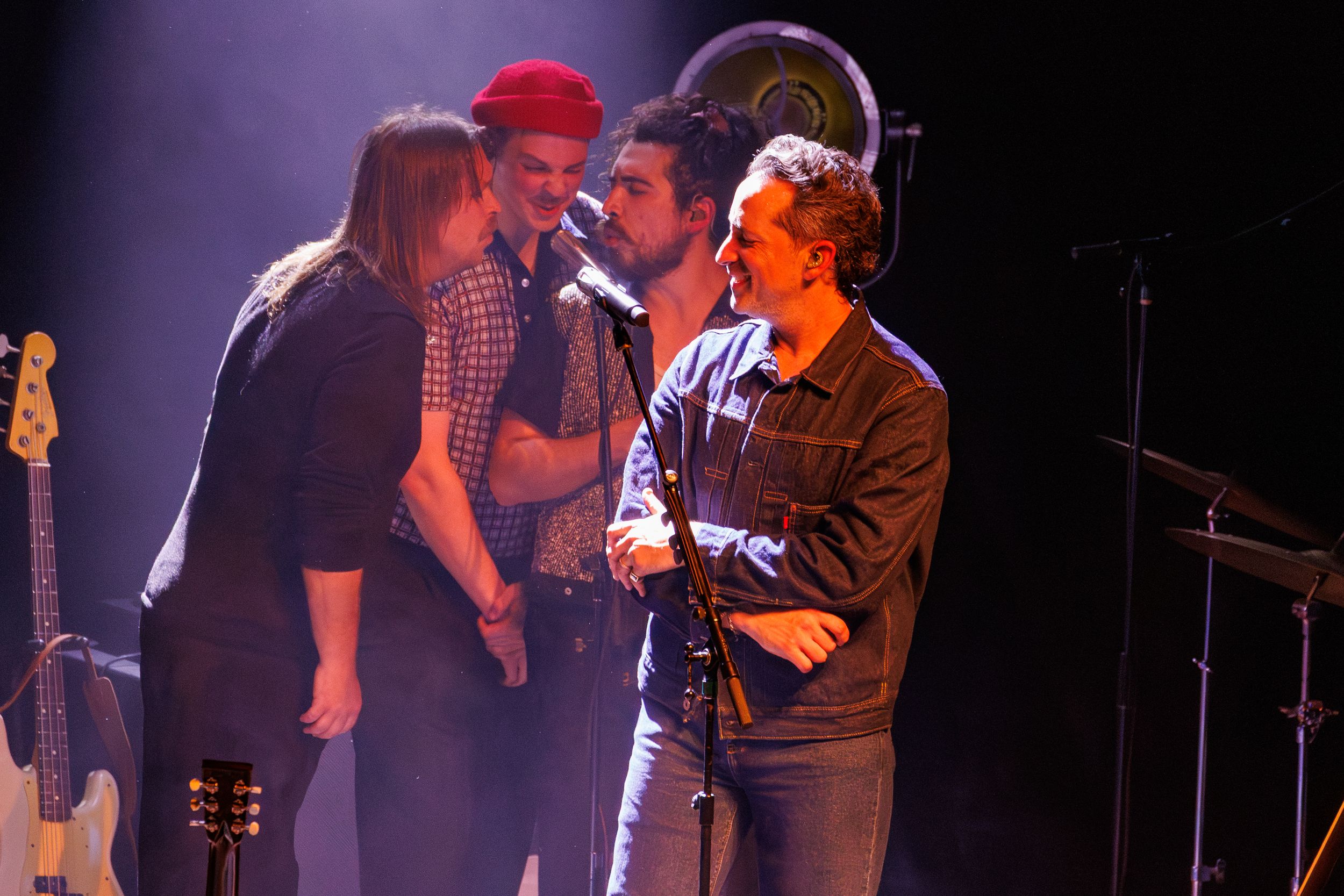 Musicians perform together on a dimly lit stage during an energetic live concert performance.