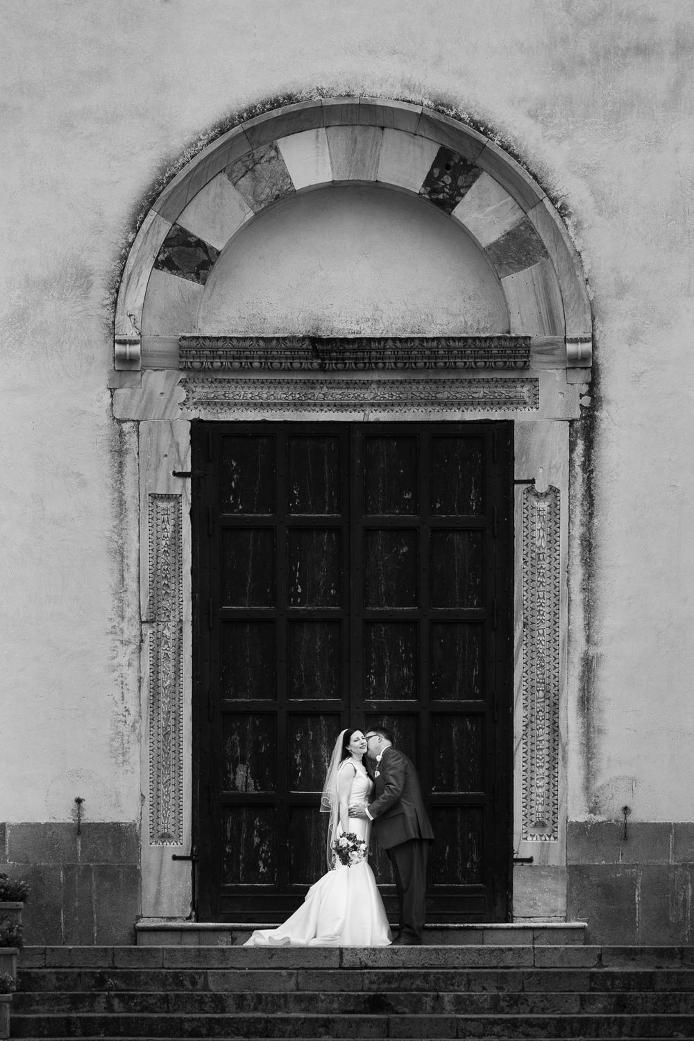 Artistic shot of bride and groom framed by large archway.