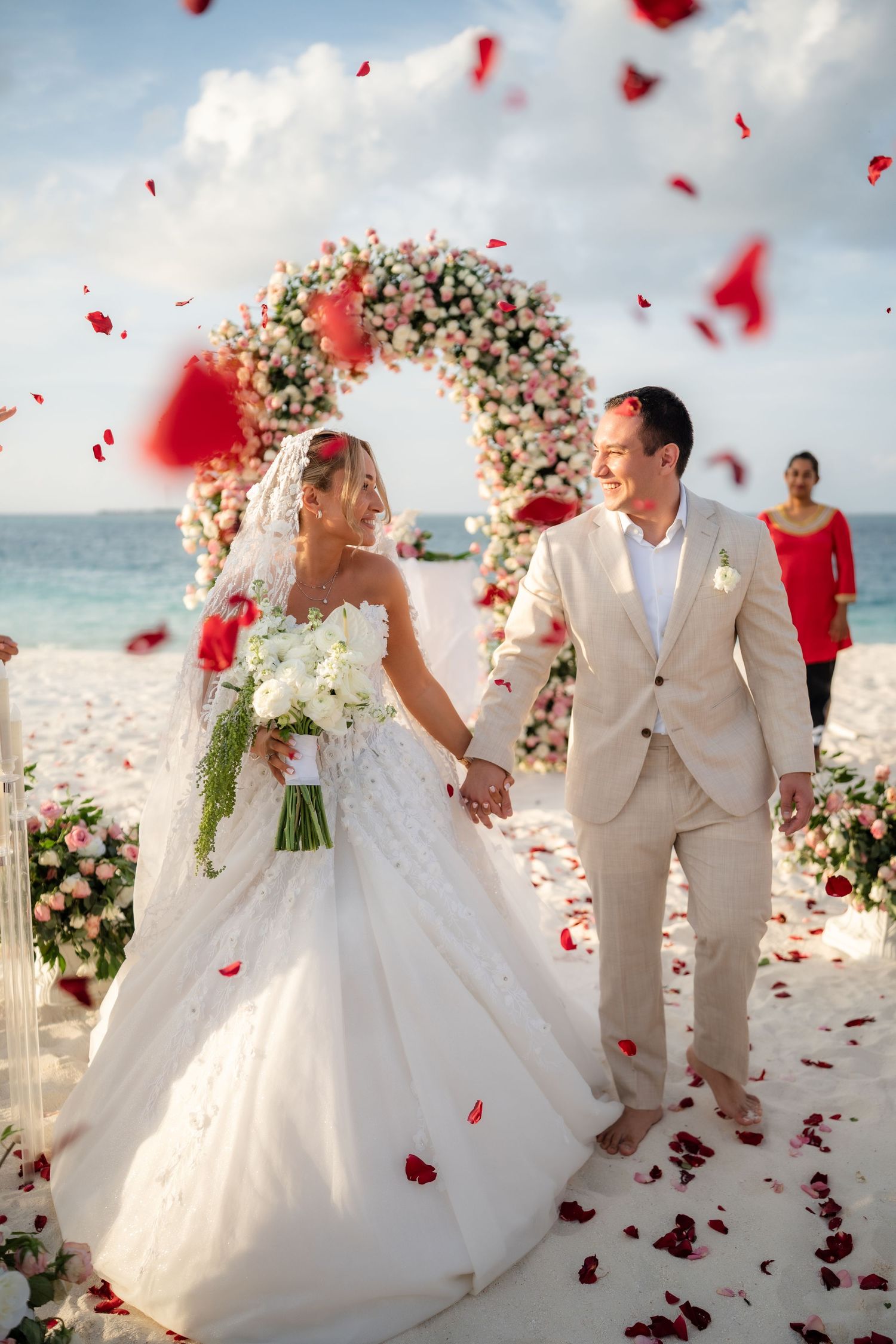 A romantic beach wedding ceremony with red rose petals floating through the air as the couple celebrates their special moment.