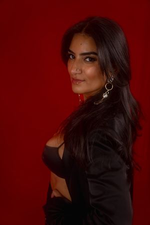 Charleston fashion studio portrait of woman in black blazer on red background.