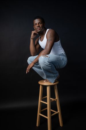 Charleston editorial style men’s studio portrait of male model seated on stool with dark background