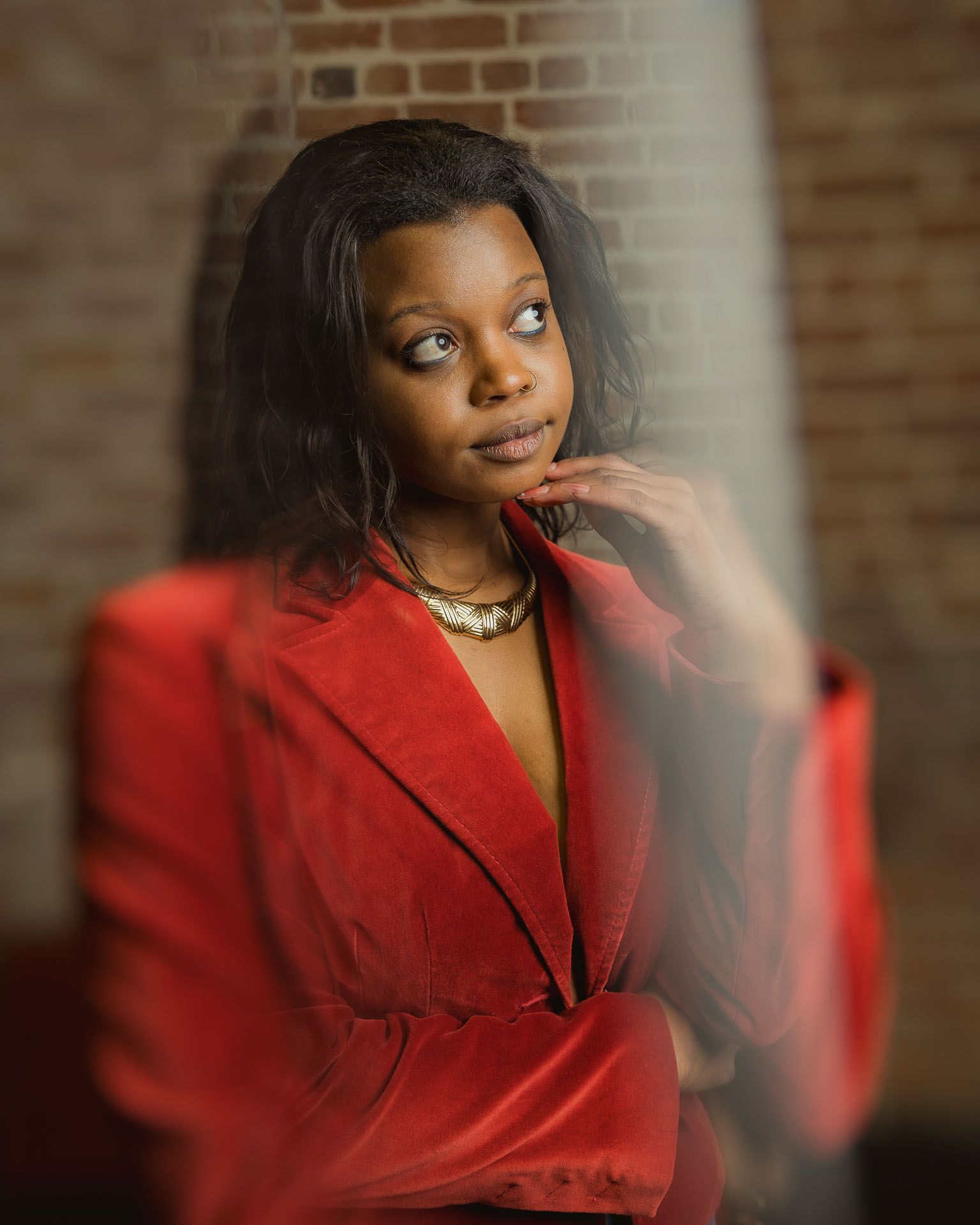 Creative Charleston studio portrait of woman in red blazer with brick wall background.