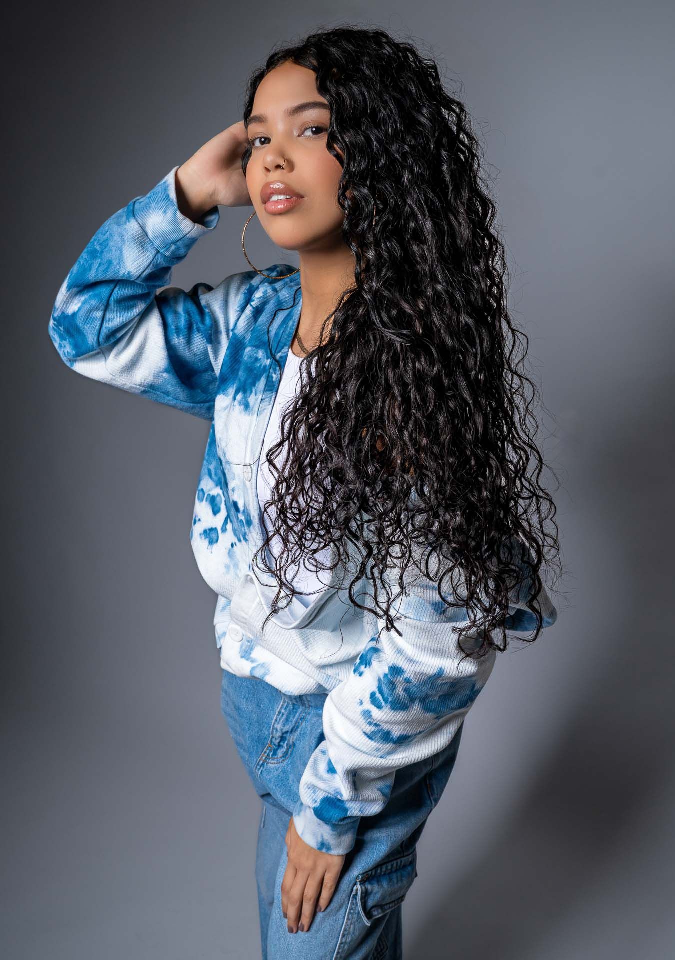Casual Charleston studio portrait of woman wearing blue tie-dye jacket and jeans on gray background.