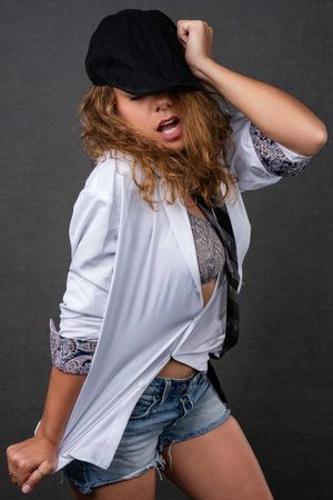 Charleston glamour studio portrait of woman in white shirt and denim shorts on gray backdrop.