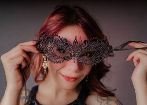 Charleston masquerade themed studio portrait of woman holding black lace mask.