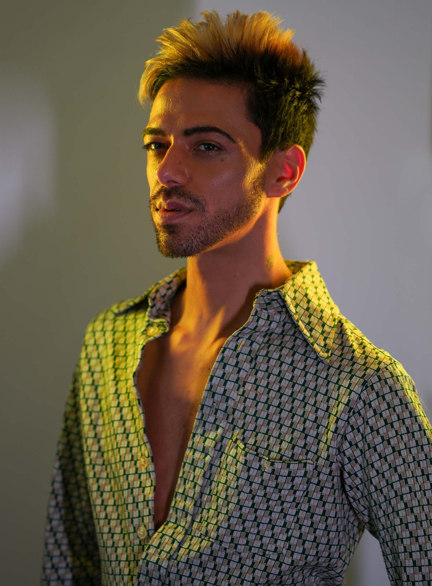 Dramatic Charleston, SC portraits showing a person in a patterned shirt against a light background with warm lighting.