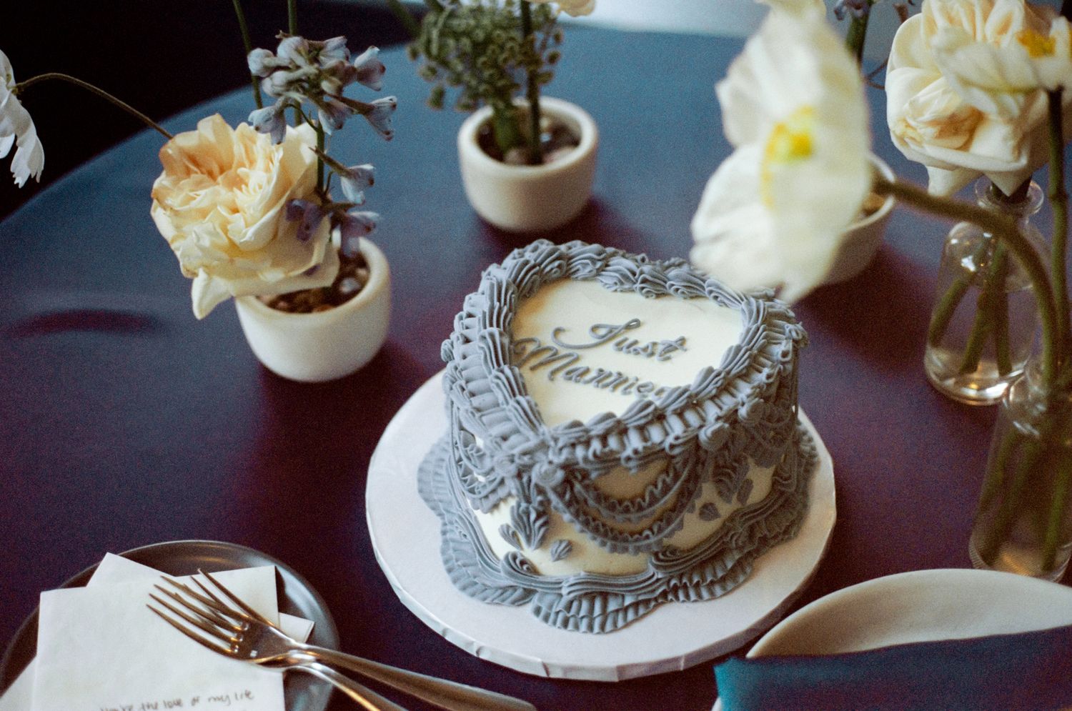 Elegant table settings with white flowers, small potted plants, and decorative silver accents create a romantic atmosphere.