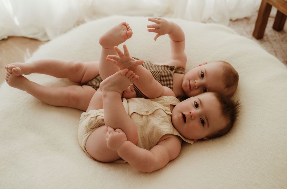A series of four photos showing a baby lying on a white blanket in different playful poses.