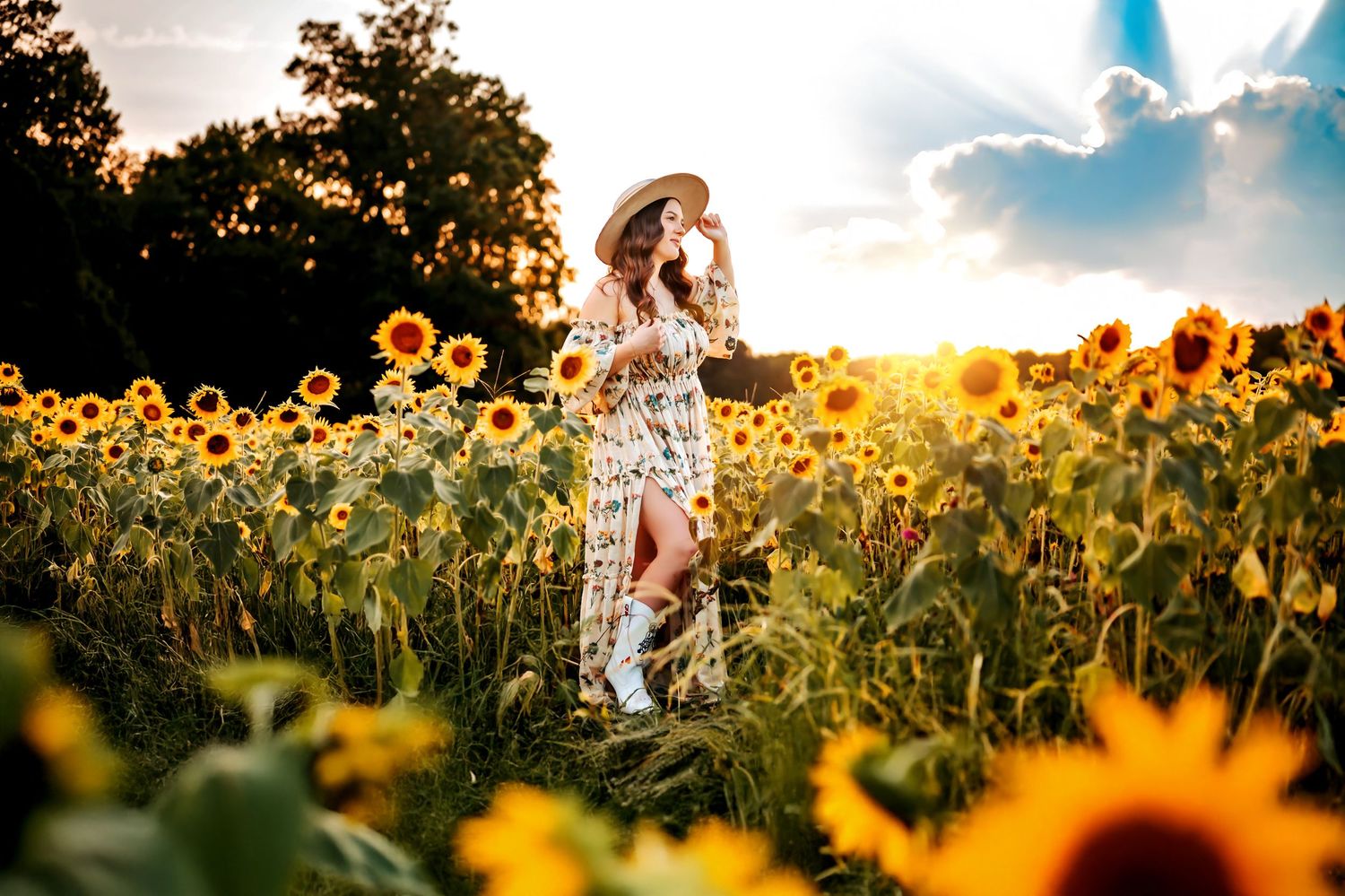 A person in a white dress walks through a vibrant sunflower field at golden hour as sunlight streams through the flowers.