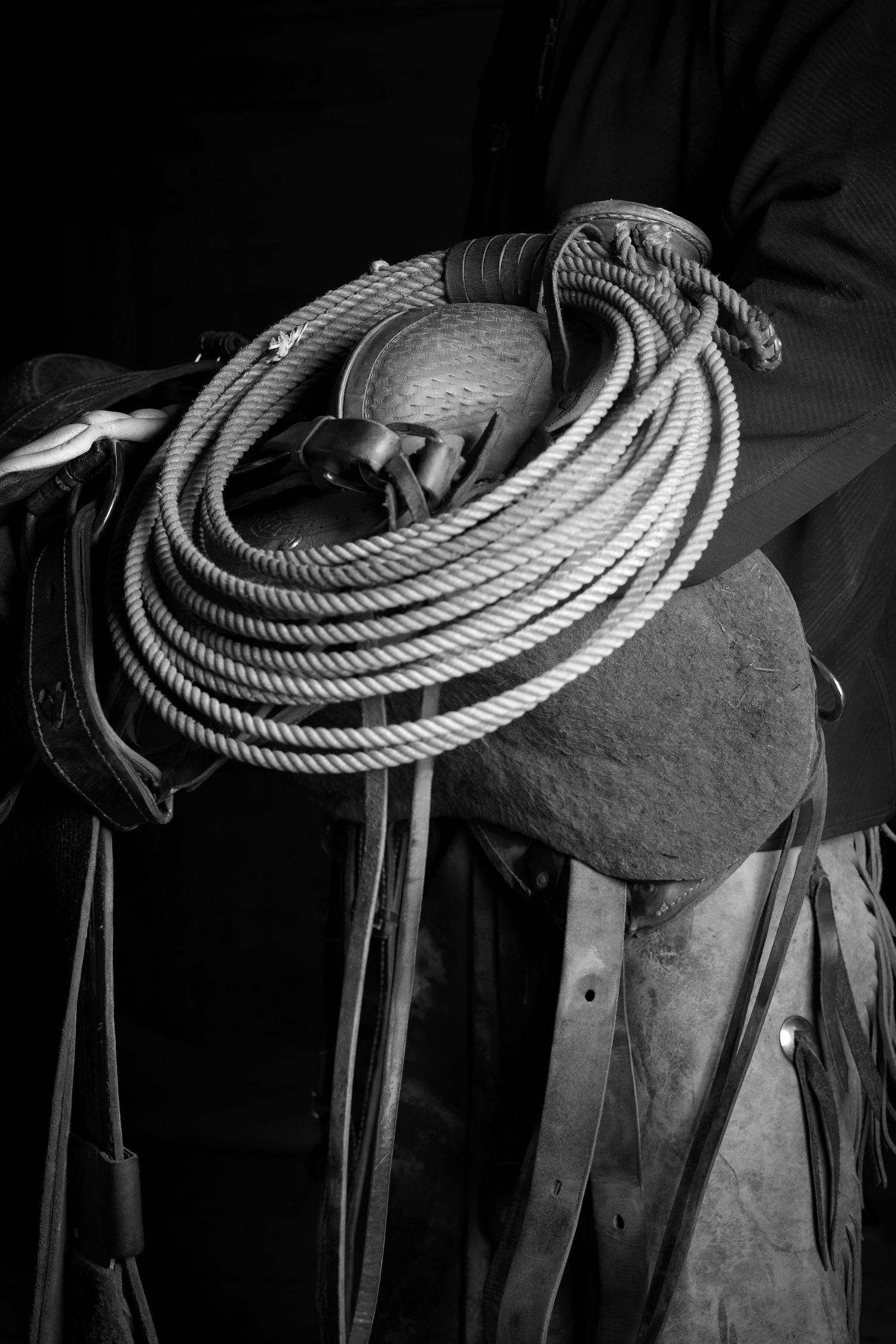 A series of black and white photos showing a coiled lasso rope resting on a western saddle.