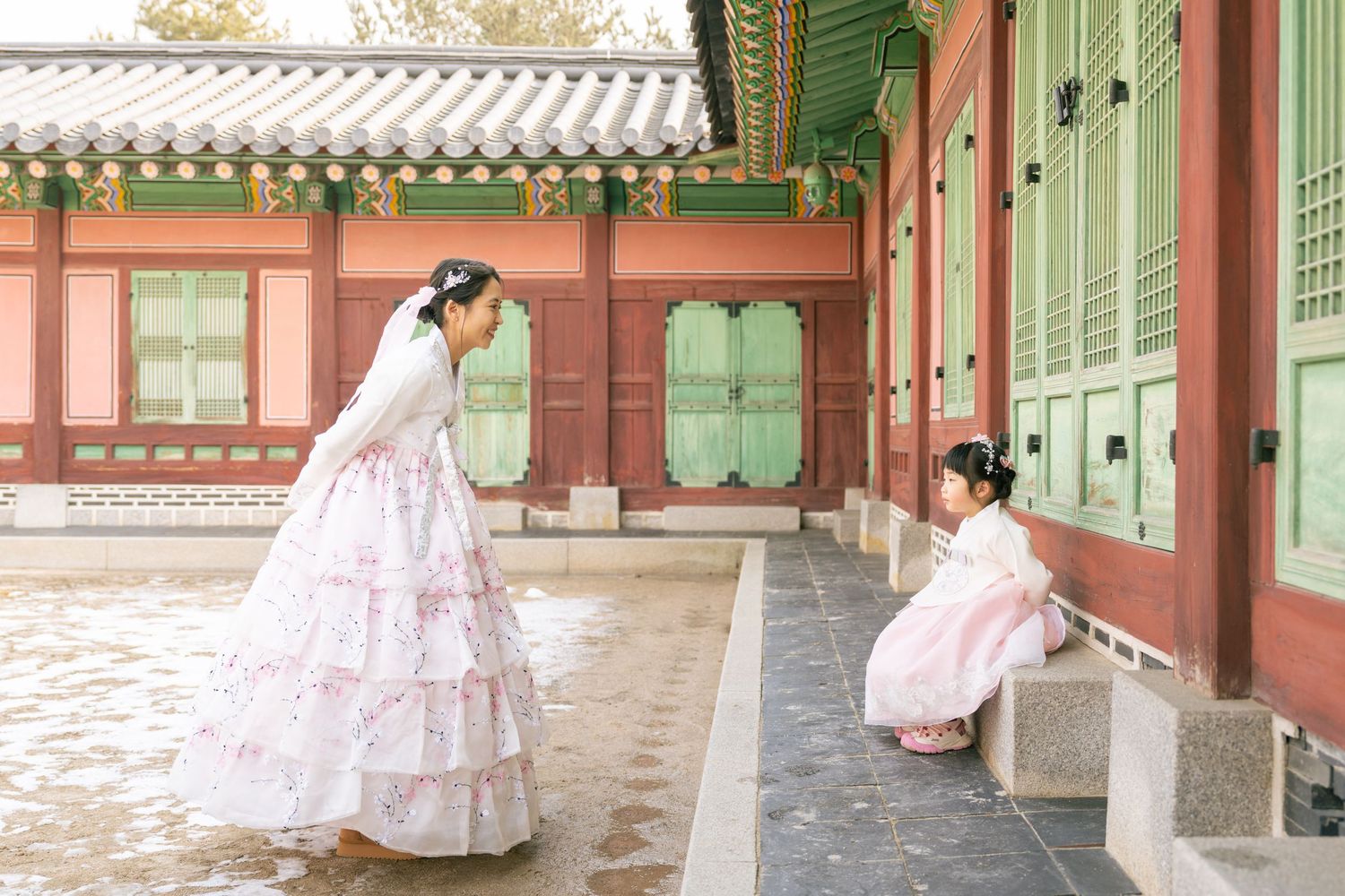 Traditional Korean hanbok-clad figures walk through the ornate wooden corridors of Gyeongbokgung Palace in Seoul.