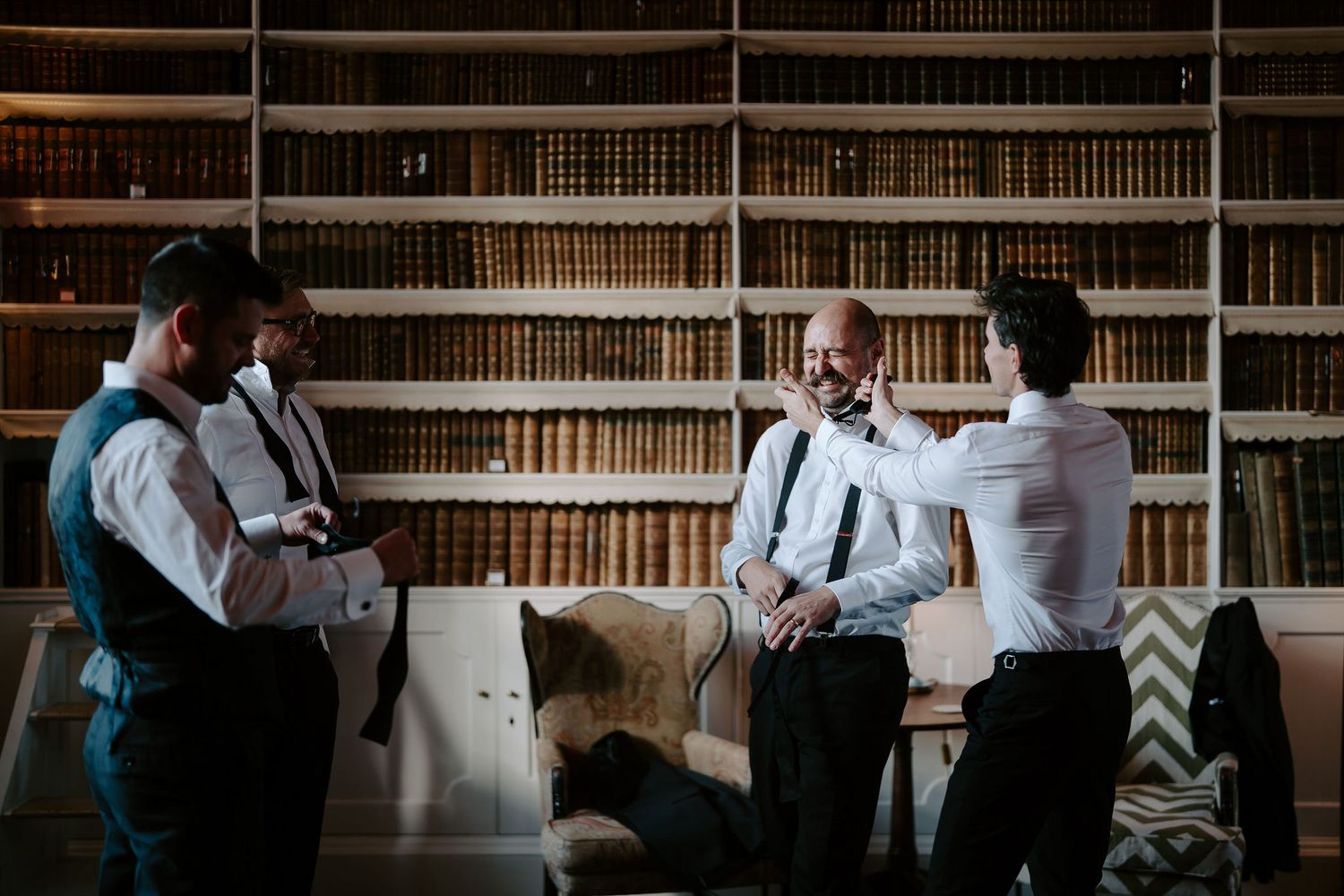 groomsman fixing groomsman's moustache in the library at Iscoyd park