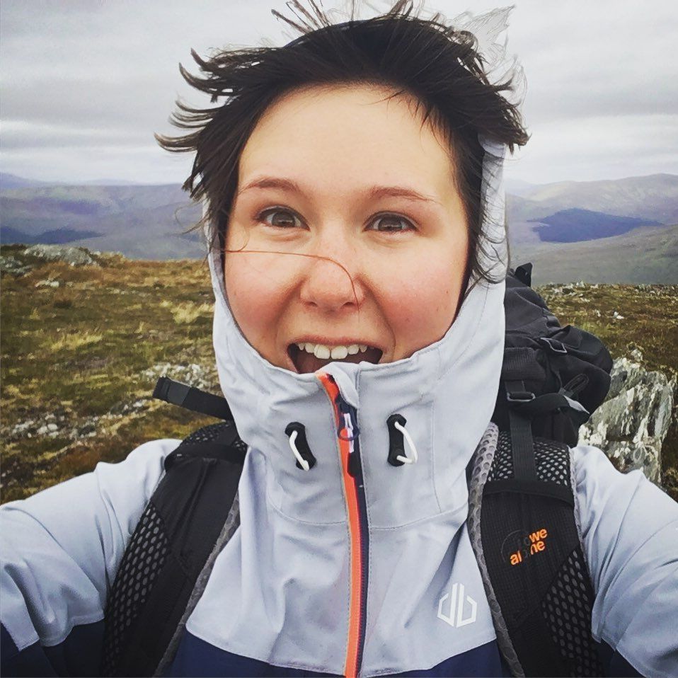 Winter sports enthusiast wearing white jacket takes selfies against mountain backdrop.