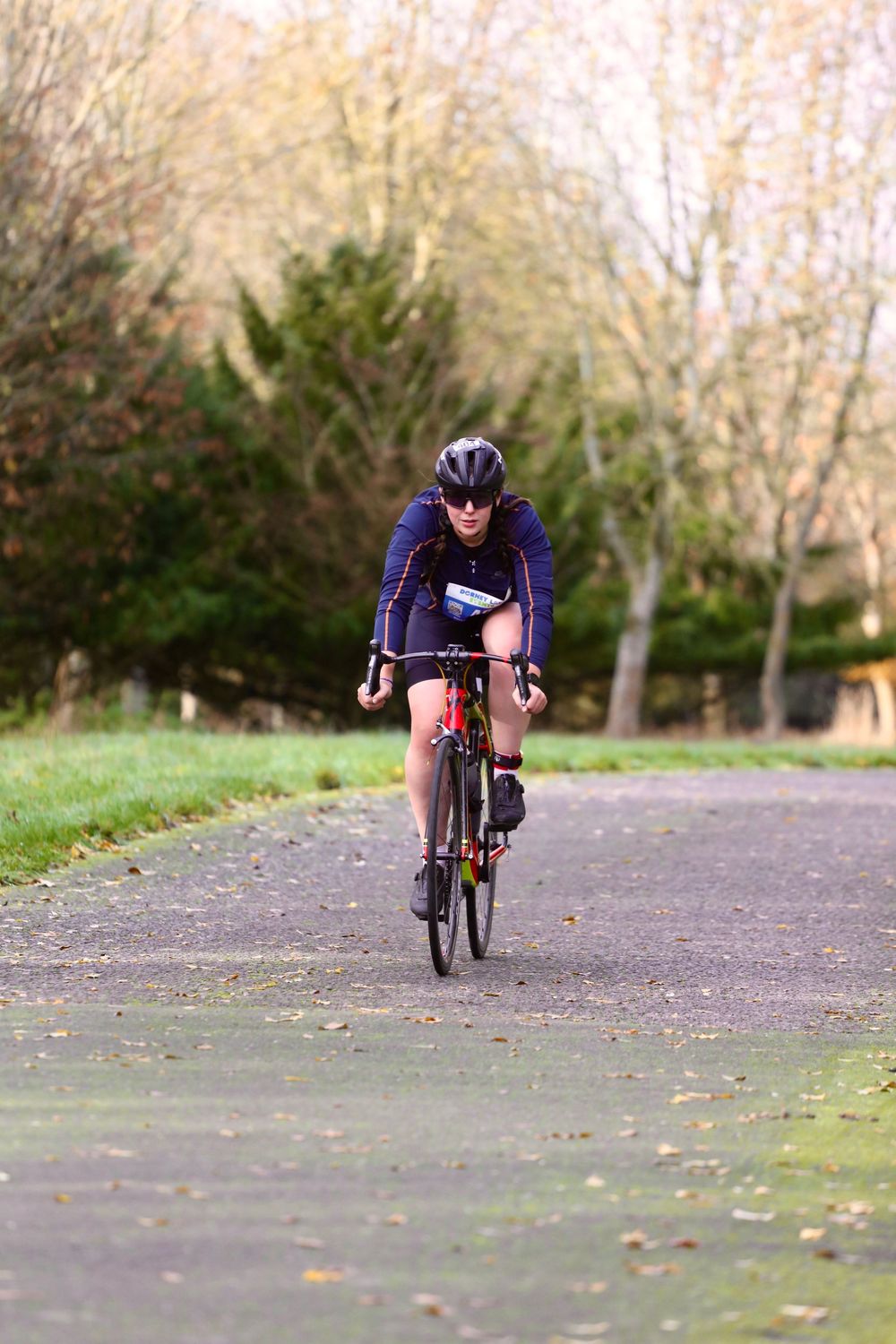 A cyclist in purple gear racing along a tree-lined path in multiple action shots.