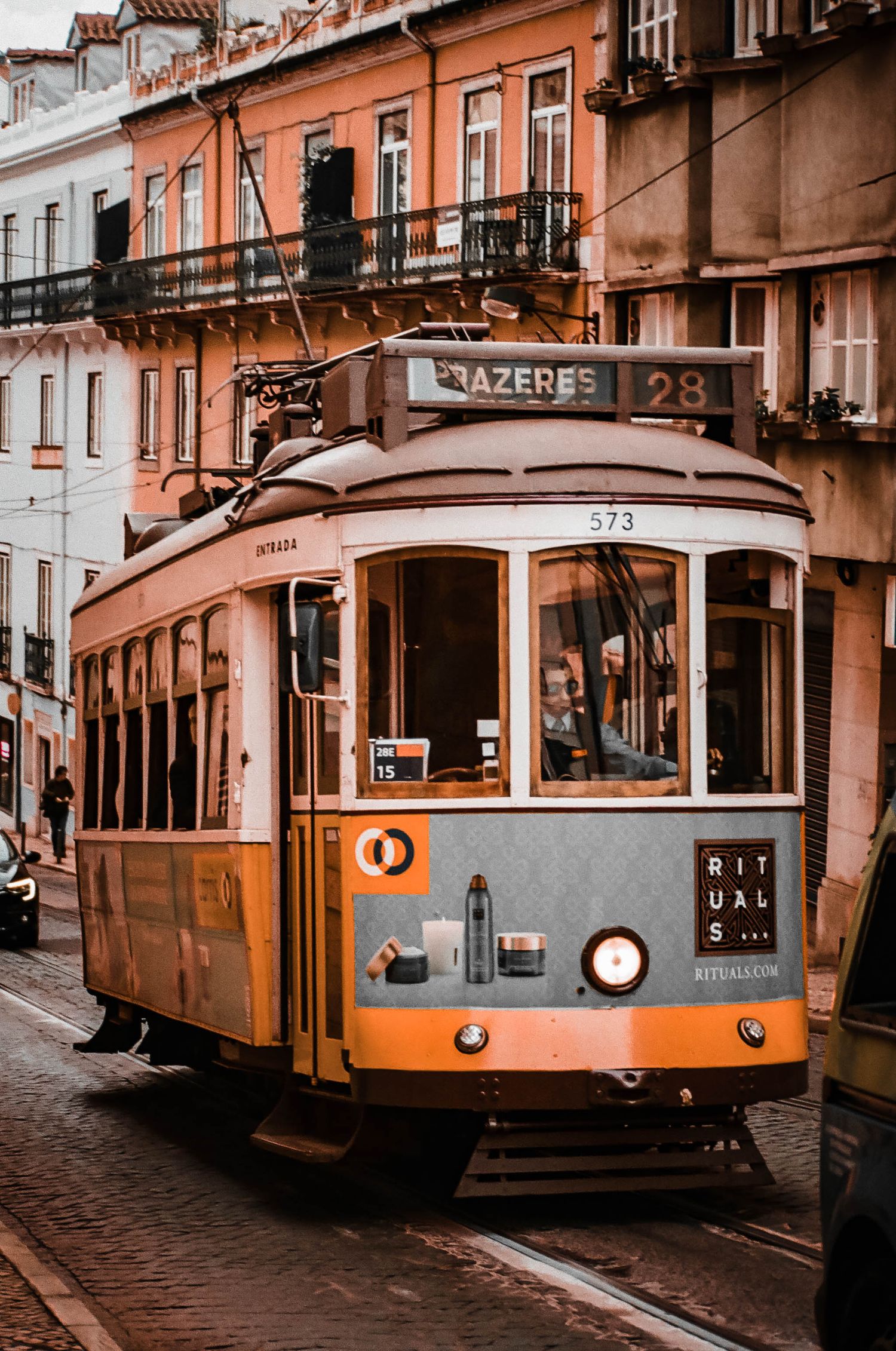 Vintage orange tram number 28 on cobblestone street in historic Lisbon, Portugal.