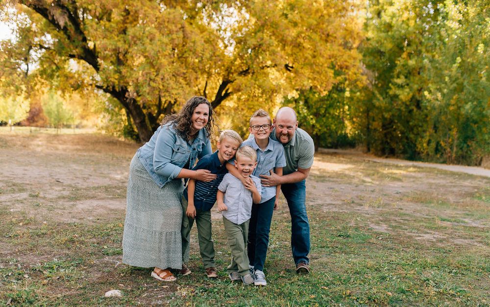 Family enjoying a golden autumn sunset together in a grassy outdoor setting.