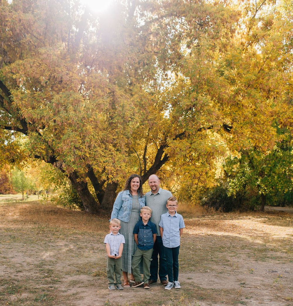 Family enjoying a warm autumn day together under golden trees in a park setting.