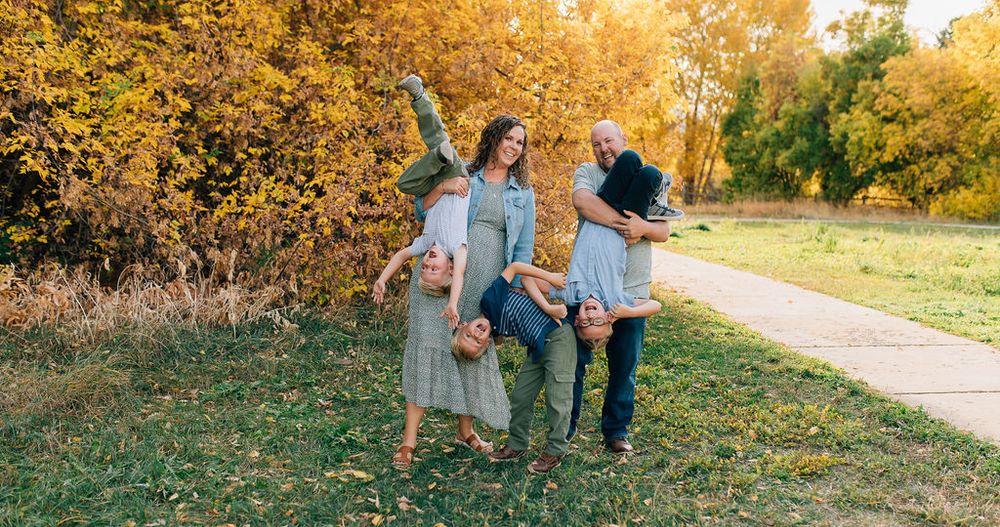 Family enjoying a golden autumn sunset in a park with fall foliage creating a warm, glowing atmosphere.