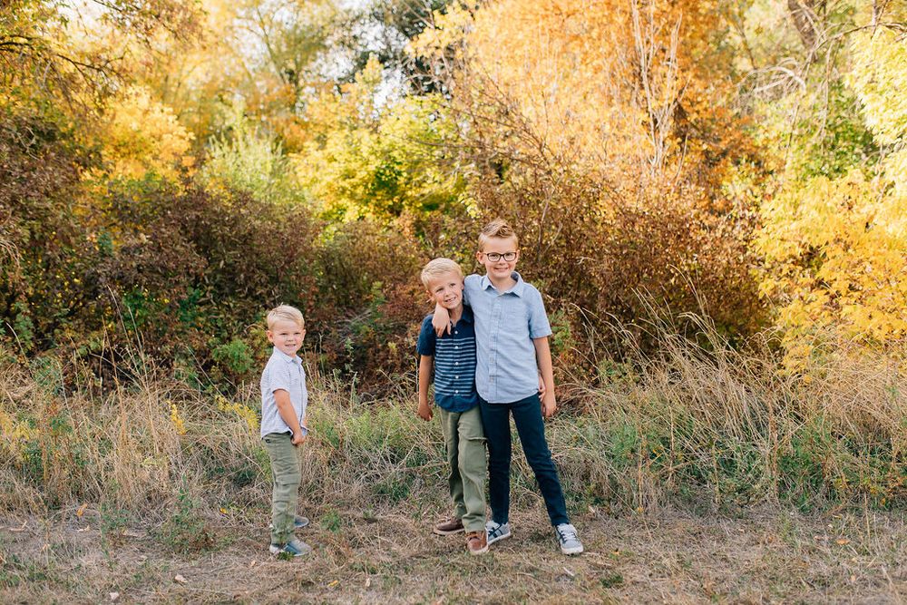 Family walking together through a scenic autumn landscape with golden trees and wooden fence.