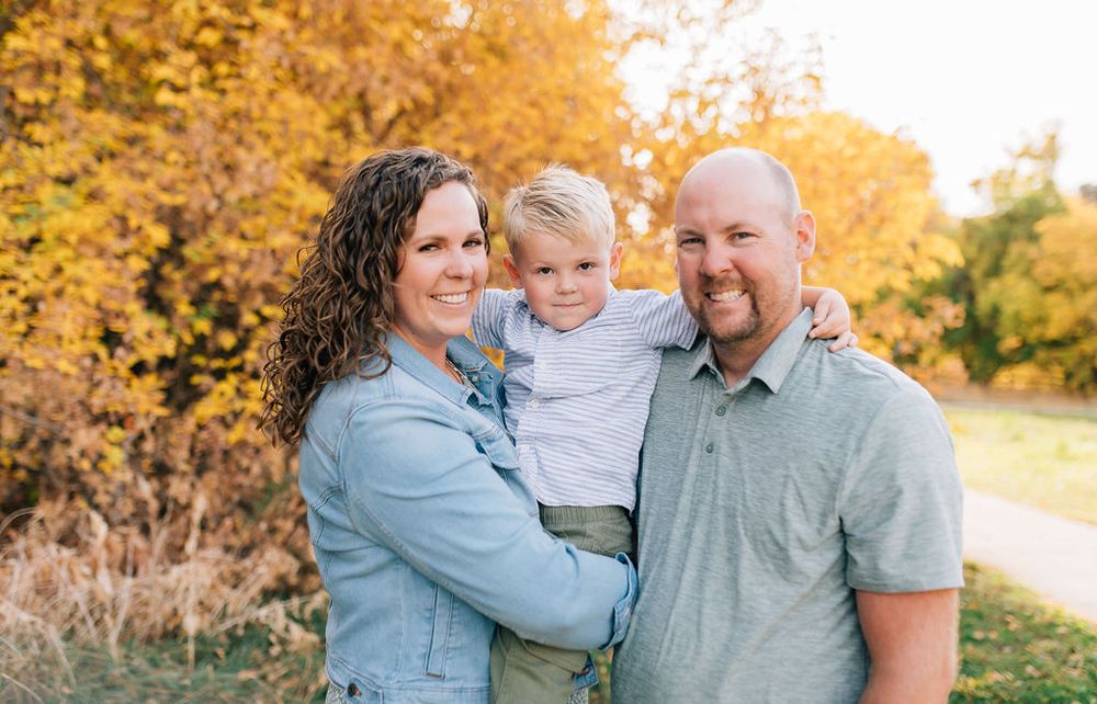 A group of people share joyful moments together in a golden autumn setting during an outdoor photo session.