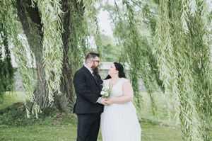 A romantic wedding photo shoot under a beautiful weeping willow tree in a garden setting.