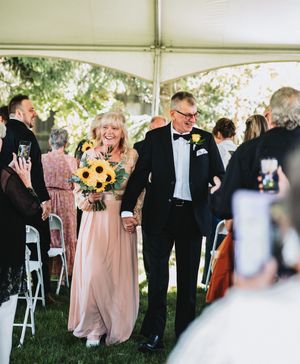 Outdoor wedding reception under a white tent with guests mingling.