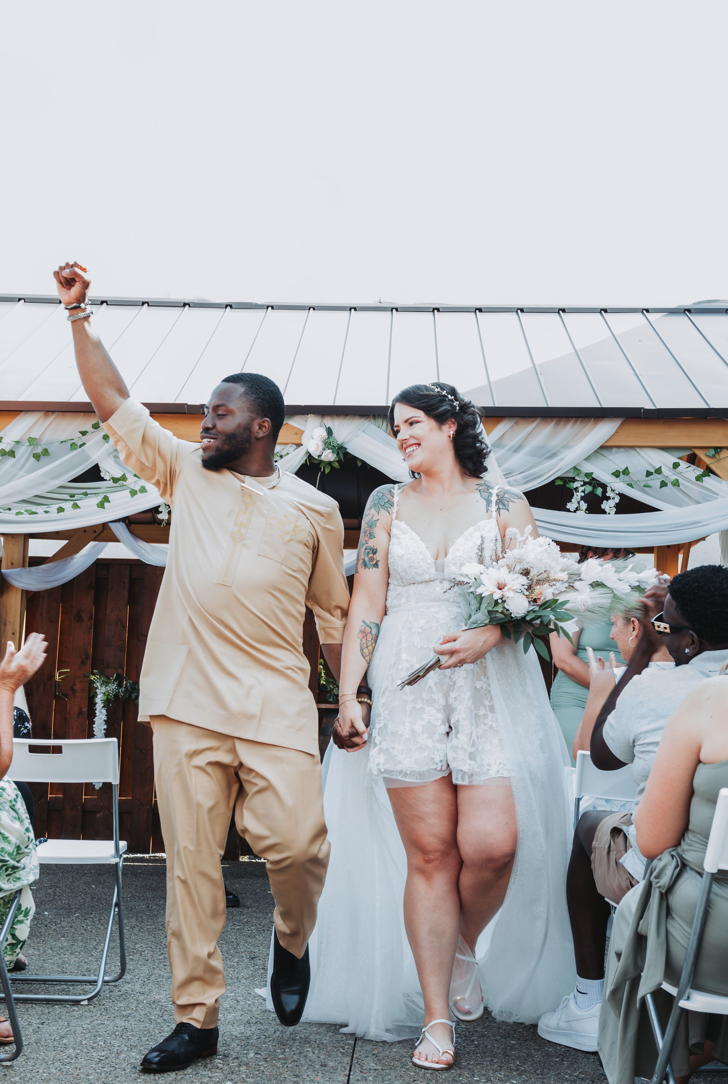 Wedding party dancing and celebrating in casual attire outdoors.