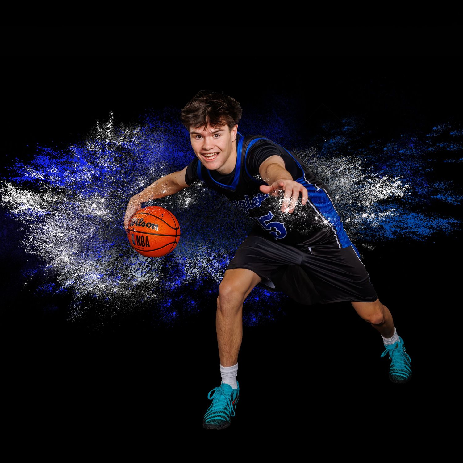 Basketball player in dark uniform dribbles through dramatic splash effect against black background with blue lighting.