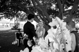 Black and white photo of an outdoor wedding ceremony under a tree.