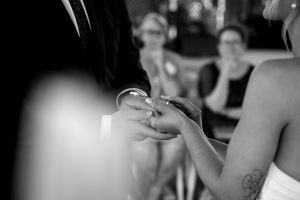 Close-up black and white shot of wedding rings being exchanged during ceremony.