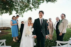 Wedding ceremony recessional with guests throwing flower petals outdoors.