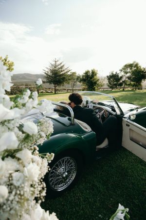 Classic vintage convertible car decorated with flowers at outdoor wedding.