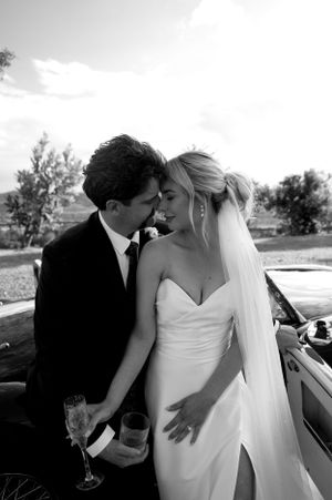 Black and white intimate moment between couple by vintage car.