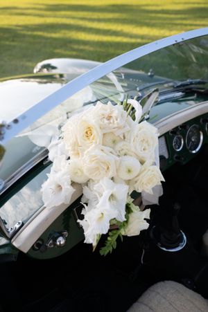Beautiful white rose and floral bouquet arranged on a classic car dashboard.