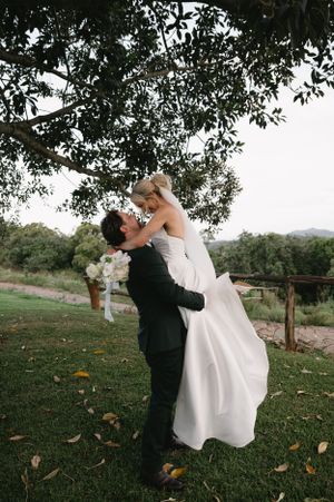 Romantic moment captured under a large tree in countryside setting.