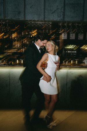 A romantic dance scene in an upscale bar with wine glasses displayed on the wall.
