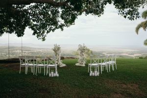Outdoor wedding ceremony setup with white chairs overlooking a valley view.