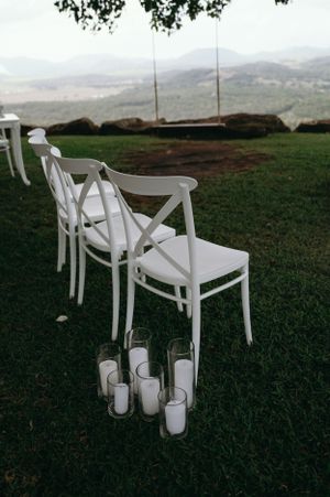 White chairs and candles set up for an outdoor ceremony with mountain views.