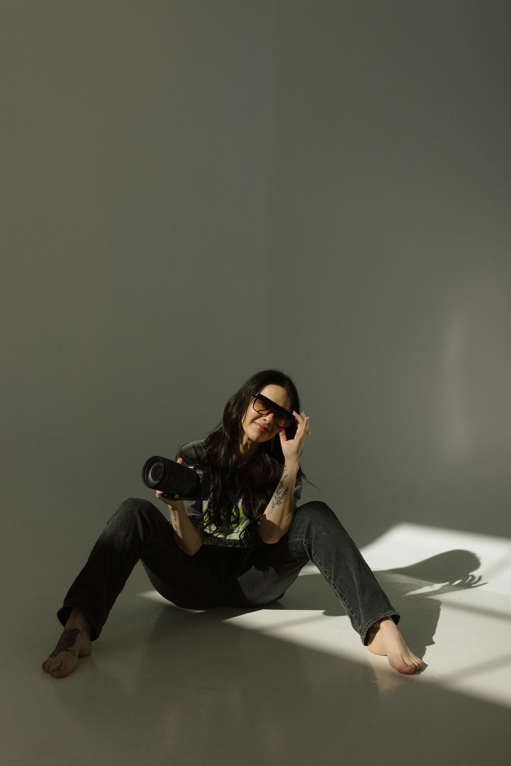 A person in black clothing lies on the floor in dramatic lighting creating an artistic silhouette series.
